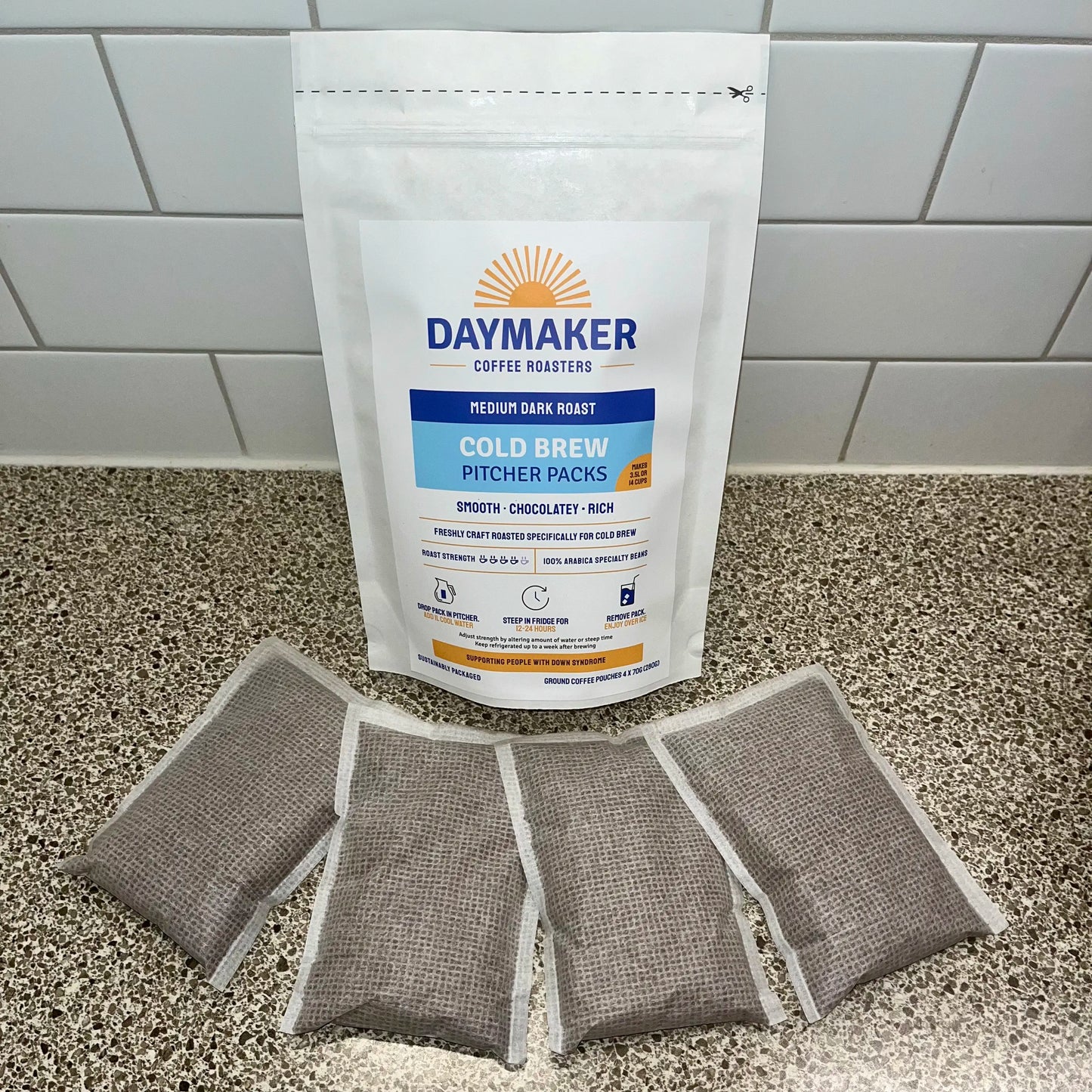 4 filter bags of coffee laying in front of a large pouch of coffee