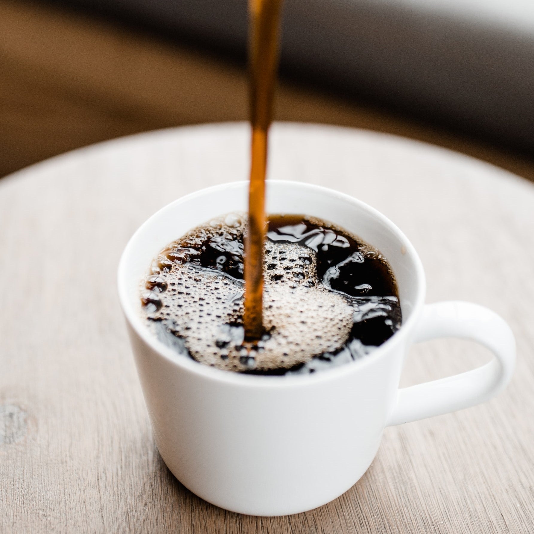 Black coffee pouring into a white mug
